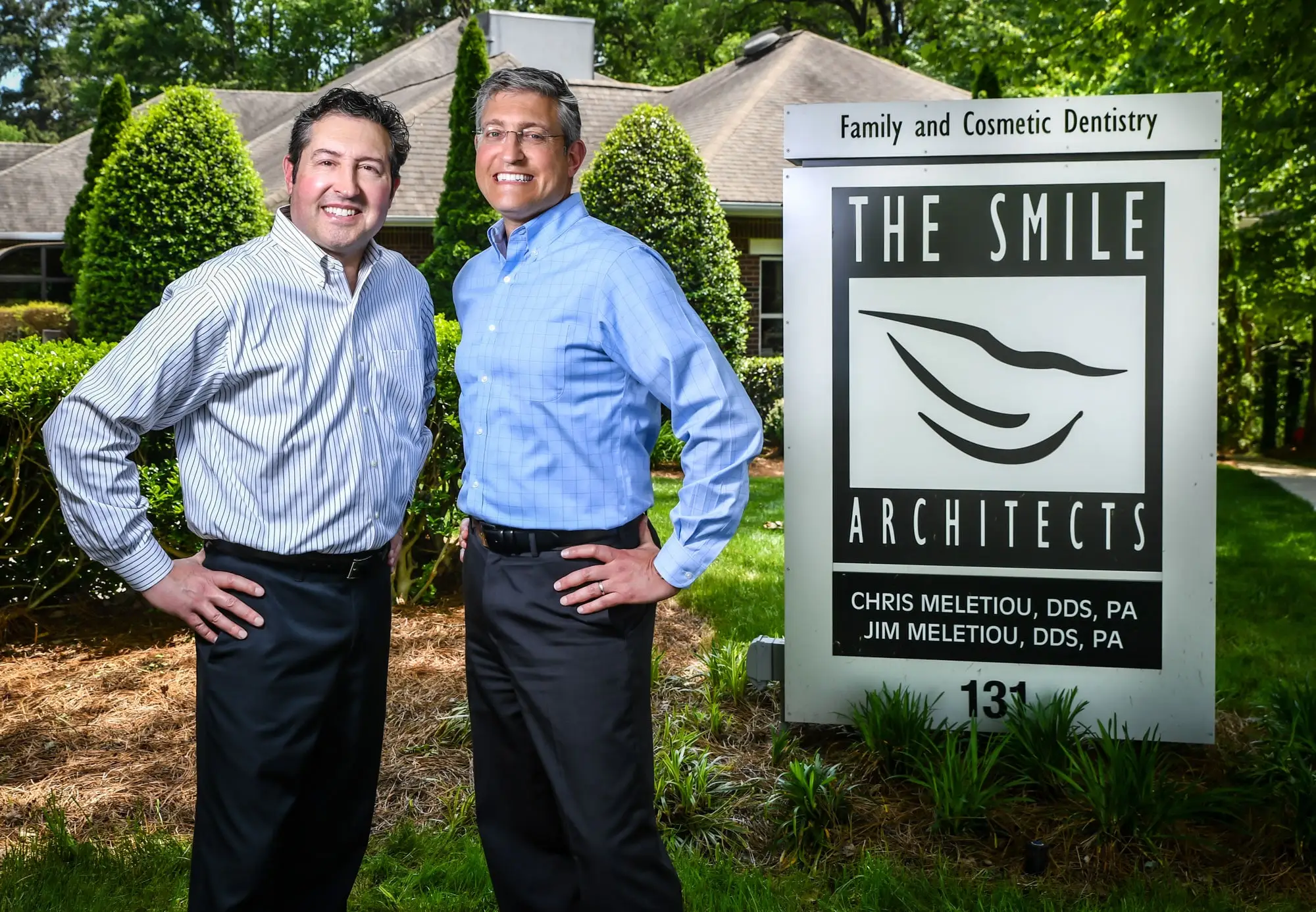 Drs. Meletiou smiling next to office sign
