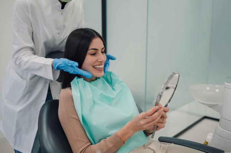 Happy patient admiring her perfect smile after dental treatment