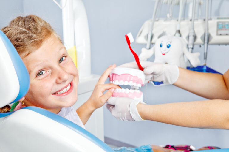 Happy child playing with toy dentures in dental office