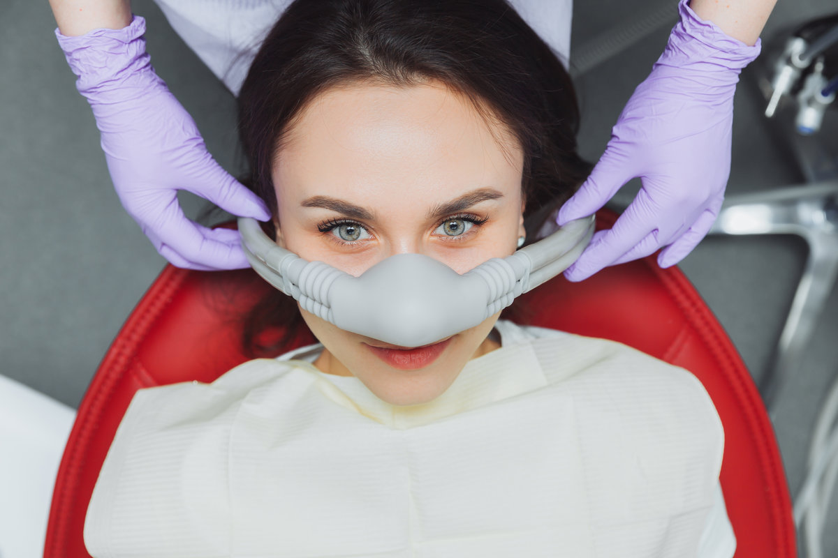 dentist puts inhalation sedative mask on his patient.