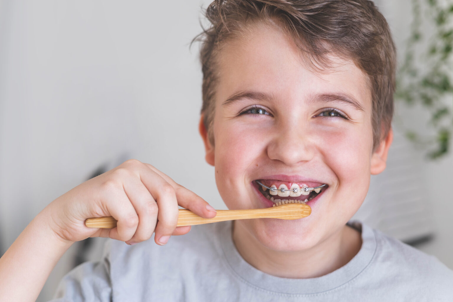 Happy boy child cleaning teeth with braces use wooden eco friendly toothbrush enjoy healthy lifestyle. Portrait overjoyed smiling male kid dental hygiene mouth stomatology toothpaste brushing closeup