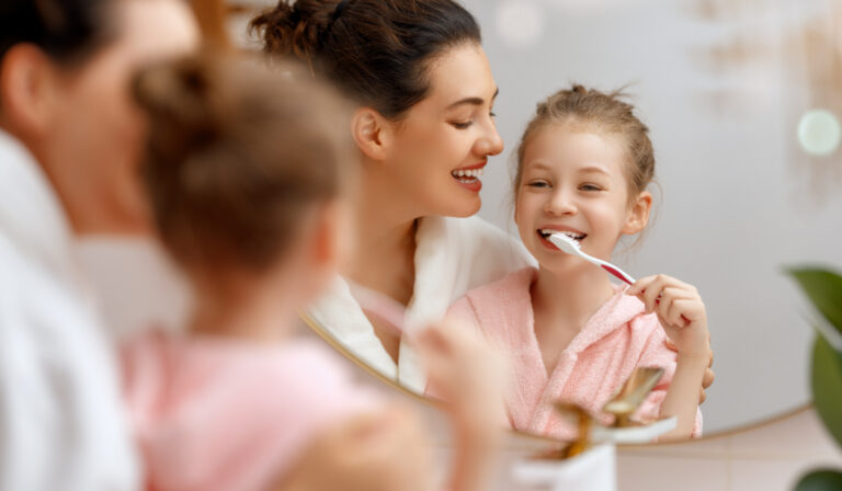 Happy family! Mother and daughter child girl are brushing teeth toothbrushes in the bathroom.